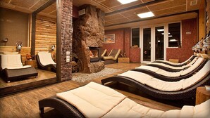 Een spa-ruimte met een stenen openhaard, lounge fauteuils en een grote spiegel.