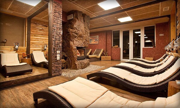 A spa room with a stone fireplace, lounge chairs, and a large mirror. - Balneo Complex & Spa Aquatonik (Velingrad)