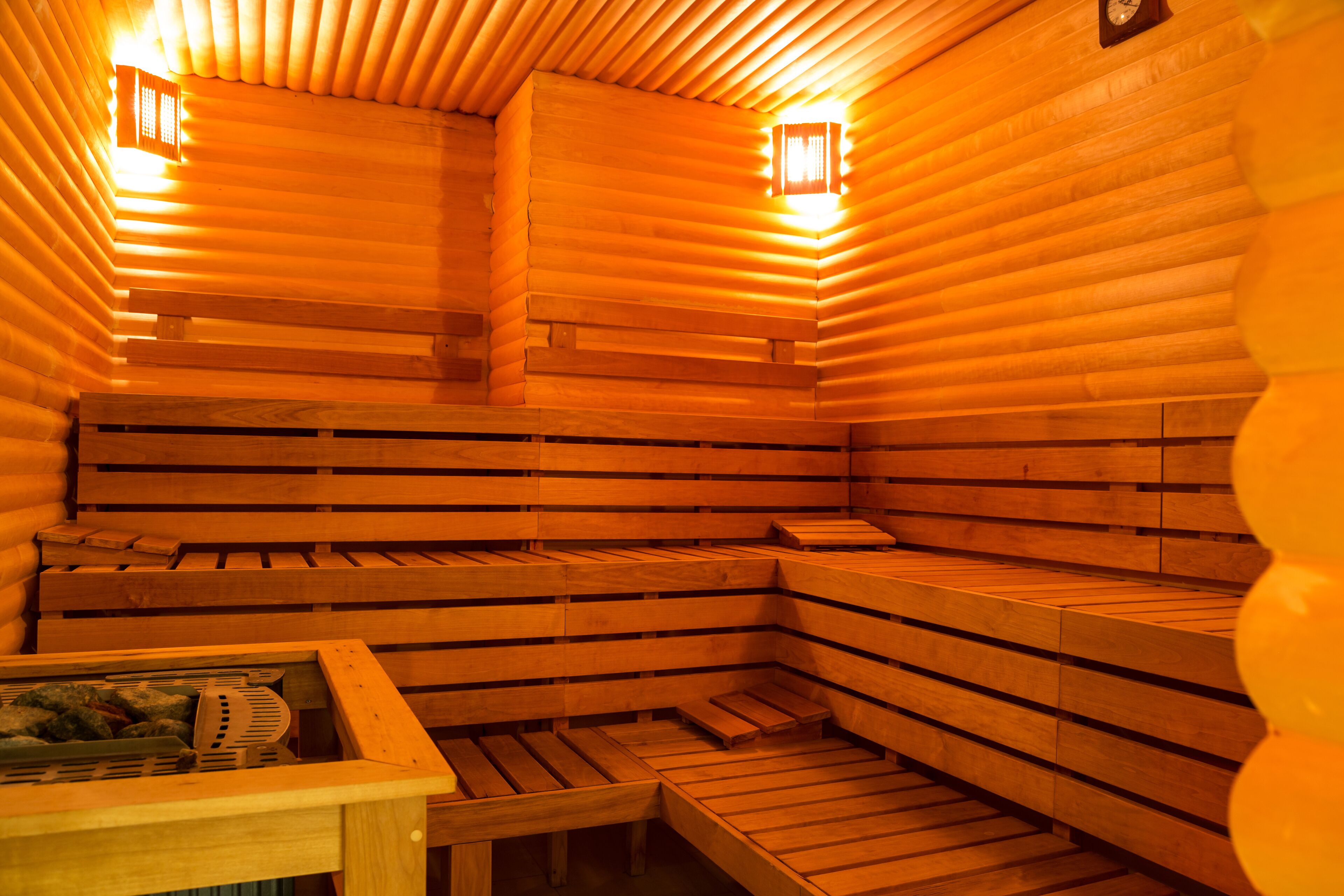 Eine Sauna mit Holzbänken, einem Holztisch und zwei Wandleuchten.