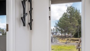 Una habitación con un banco, una puerta que da al exterior y vistas a una zona verde con árboles.