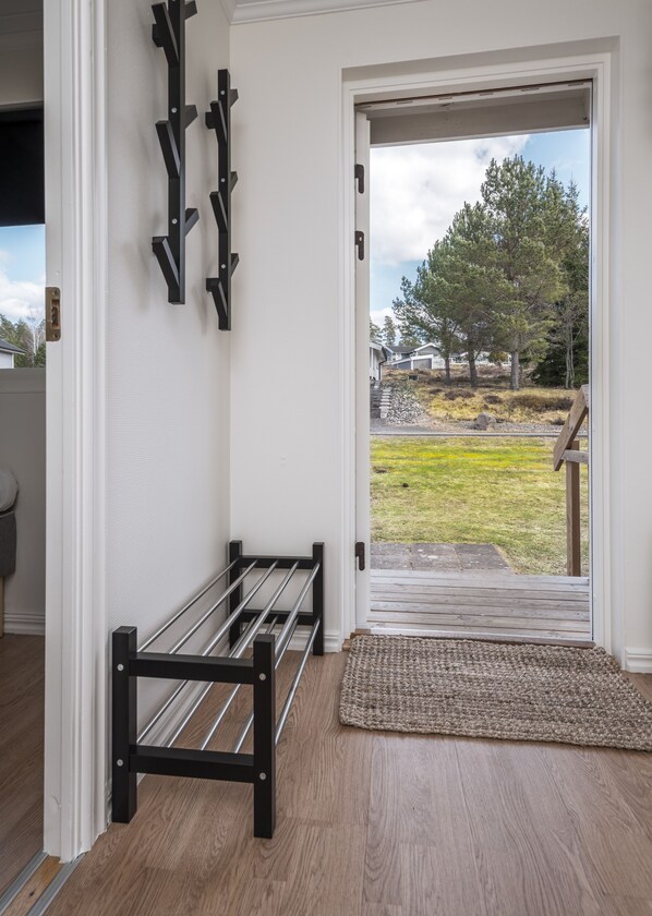 A room with a bench, a door leading outside, and a view of a grassy area with trees. - Isaberg Golfklubb (Hestra)