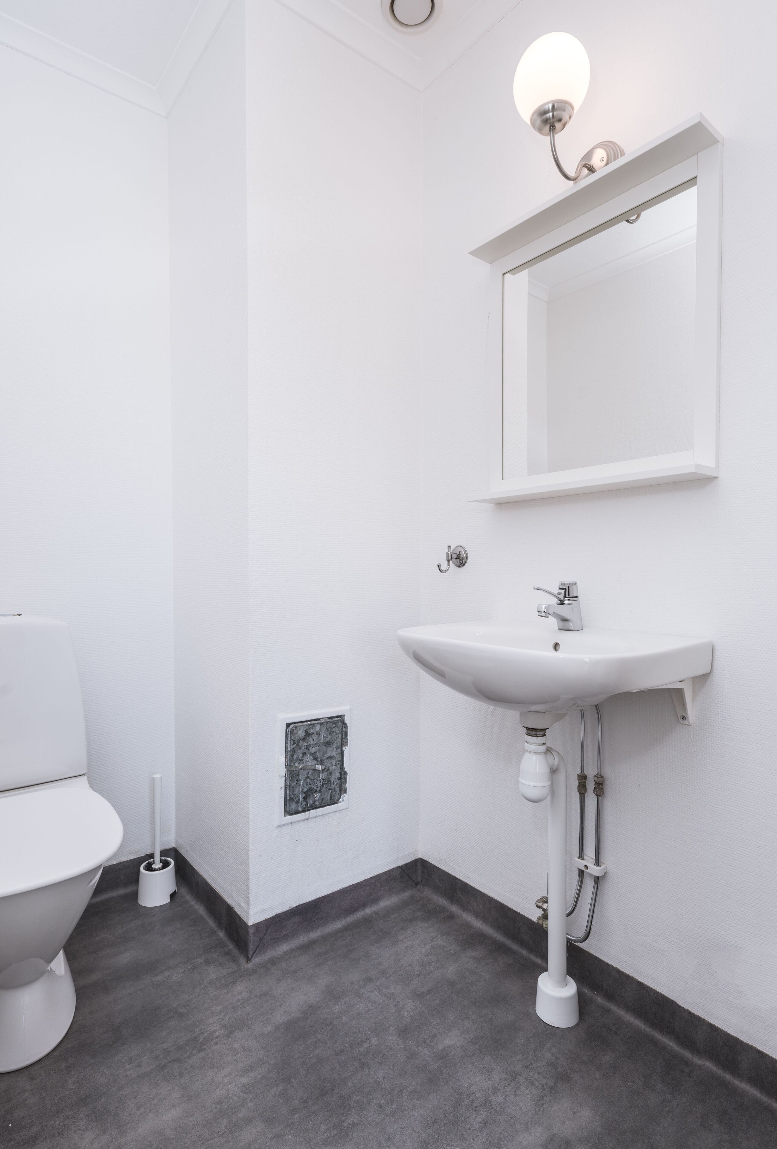 Een moderne badkamer met een witte wastafel, spiegel en toilet.