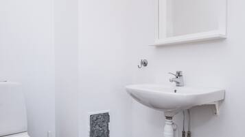 Een moderne badkamer met een witte wastafel, spiegel en toilet.