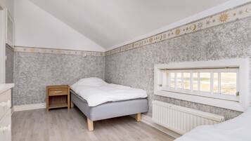 A bedroom with a bed, a nightstand, a window with a view, and a radiator.
