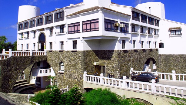 Un immeuble à plusieurs étages, doté d’une façade blanche, d’un socle en pierre et de balcons.