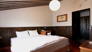 Une chambre à coucher avec une tête de lit en bois, un lit avec une literie blanche, une table de chevet avec un téléphone et un tableau encadré au mur.