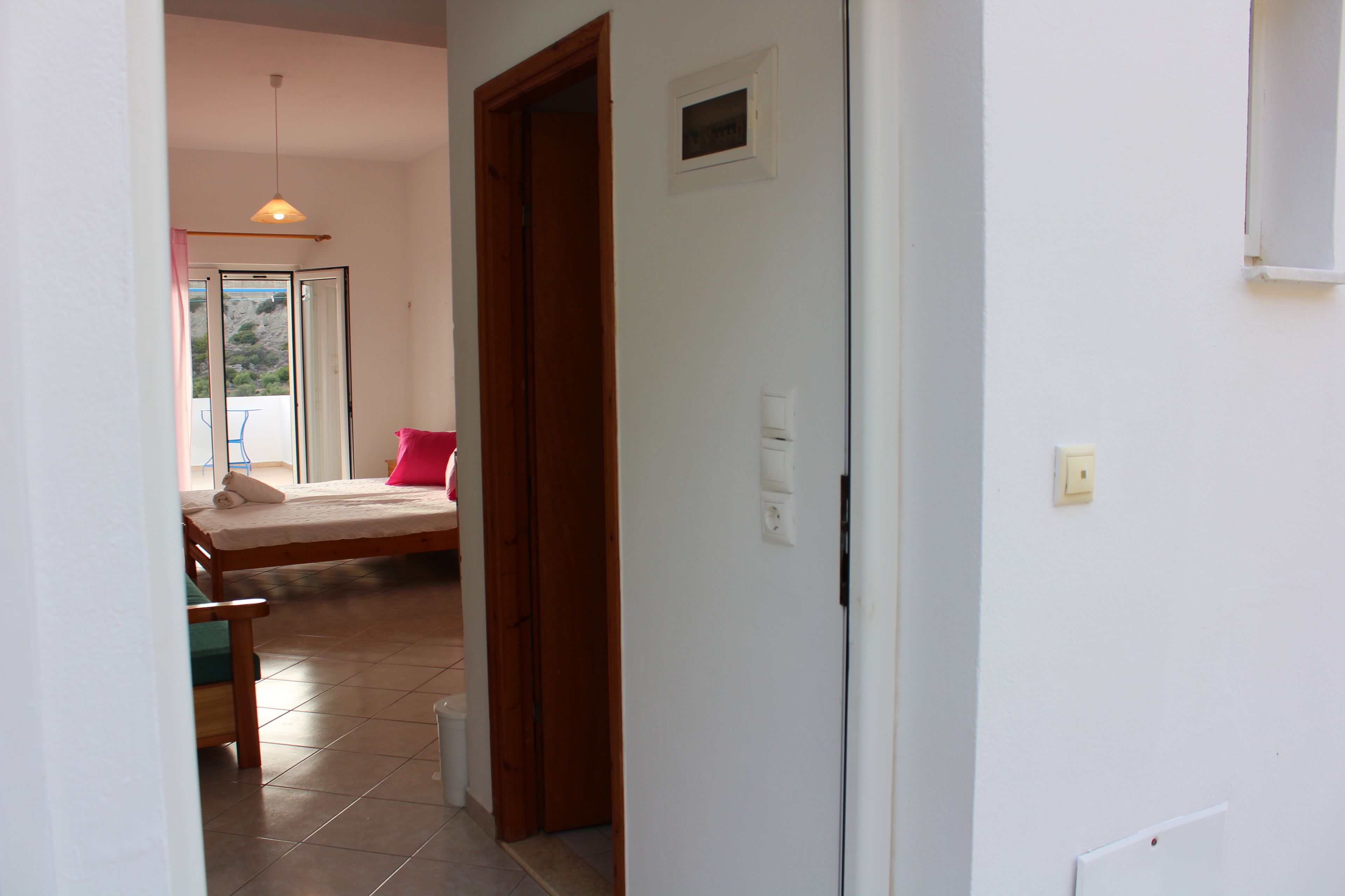 Una habitación con cama, una silla, una puerta de madera y una ventana.