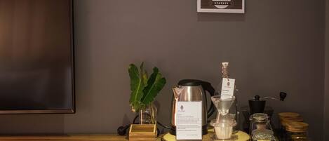 A coffee station with a coffee maker, grinder, and various containers on a wooden table.