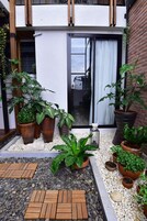 Een binnenplaats met plantenpotten, een lantaarn en een houten bankje.