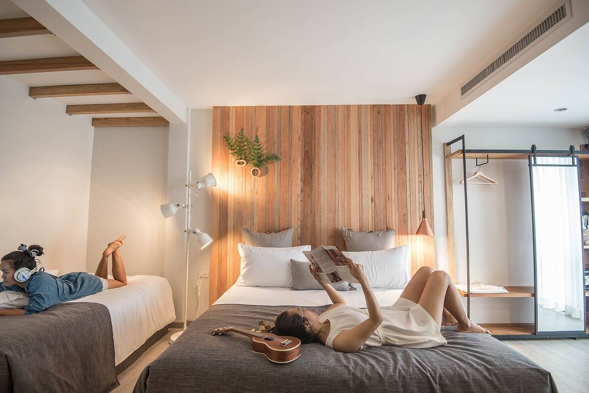 A modern bedroom with two beds, a wooden accent wall, and a walk-in closet.