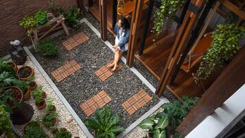 A courtyard with a wooden bench, potted plants, and a person sitting.