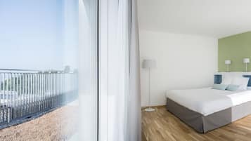 A modern hotel room with a large bed, a desk, and a view of the city.