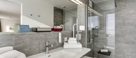 Ein modernes Badezimmer mit einem großen Spiegel, einem weißen Waschbecken, einer Toilette und einer Duschkabine.