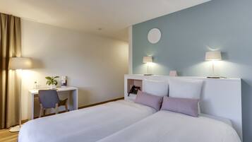 Ein Hotelzimmer mit Bett, Schreibtisch, Stuhl und zwei Nachttischlampen.