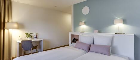 A hotel room with a bed, desk, chair, and two bedside lamps.