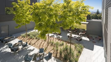 Un patio con mobiliario exterior, árboles y vistas de los edificios circundantes.