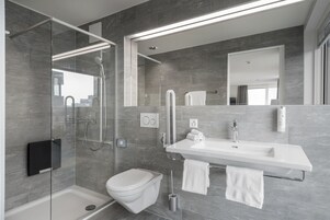 Un baño moderno con ducha acristalada, un lavabo blanco y un inodoro.