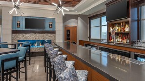 A modern bar area with a long counter, bar stools, and a fireplace.