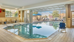 An indoor swimming pool with a tiled floor, a glass barrier, and a lifeguard chair.