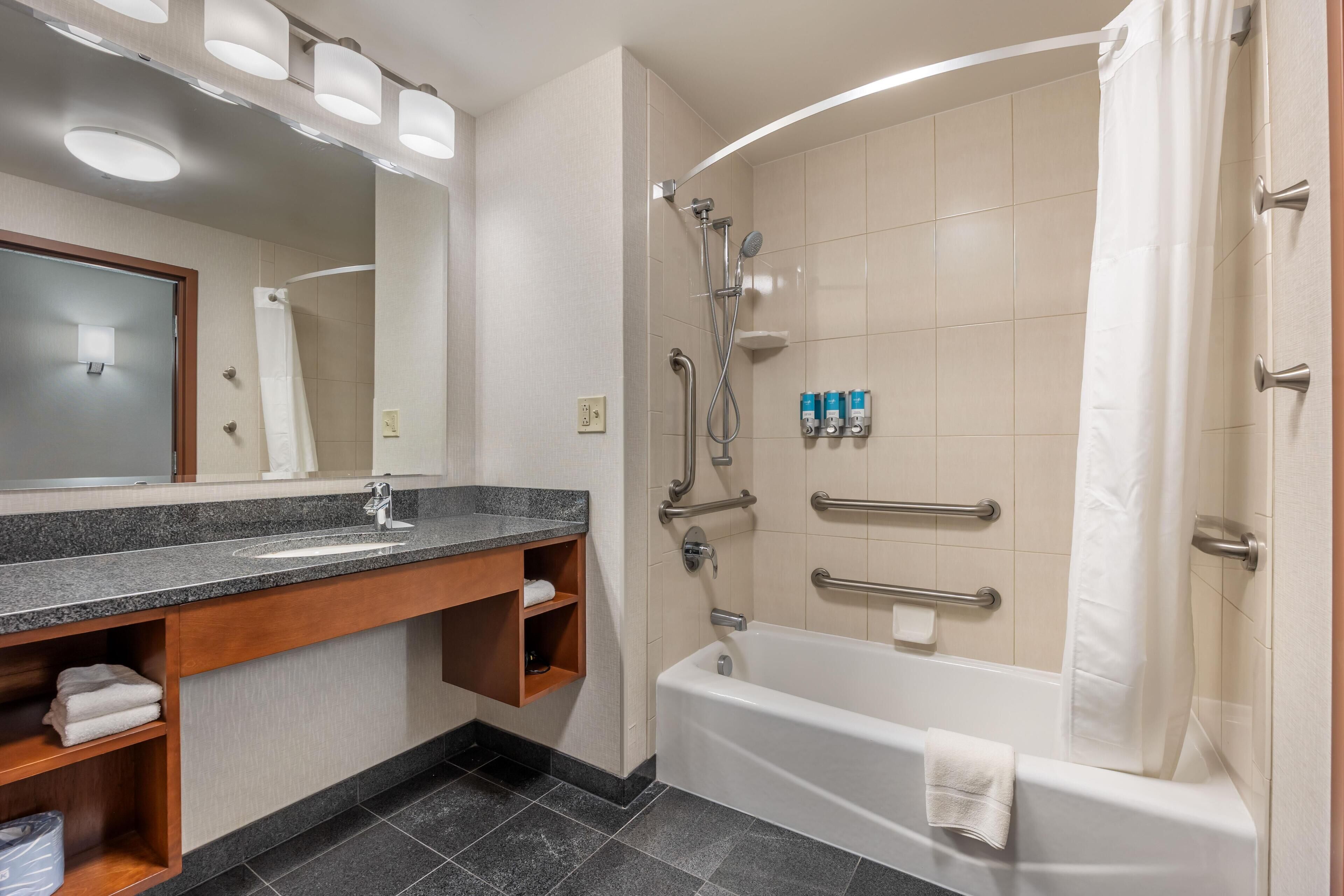 A modern bathroom with a bathtub, shower, and vanity.