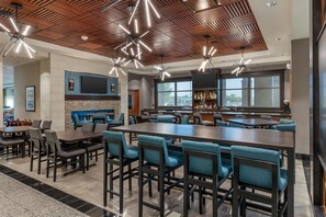 A spacious bar area with high tables and chairs, a large flat-screen TV mounted on the wall, and a bar stocked with bottles. - Drury Plaza Hotel Columbia East (Columbia)