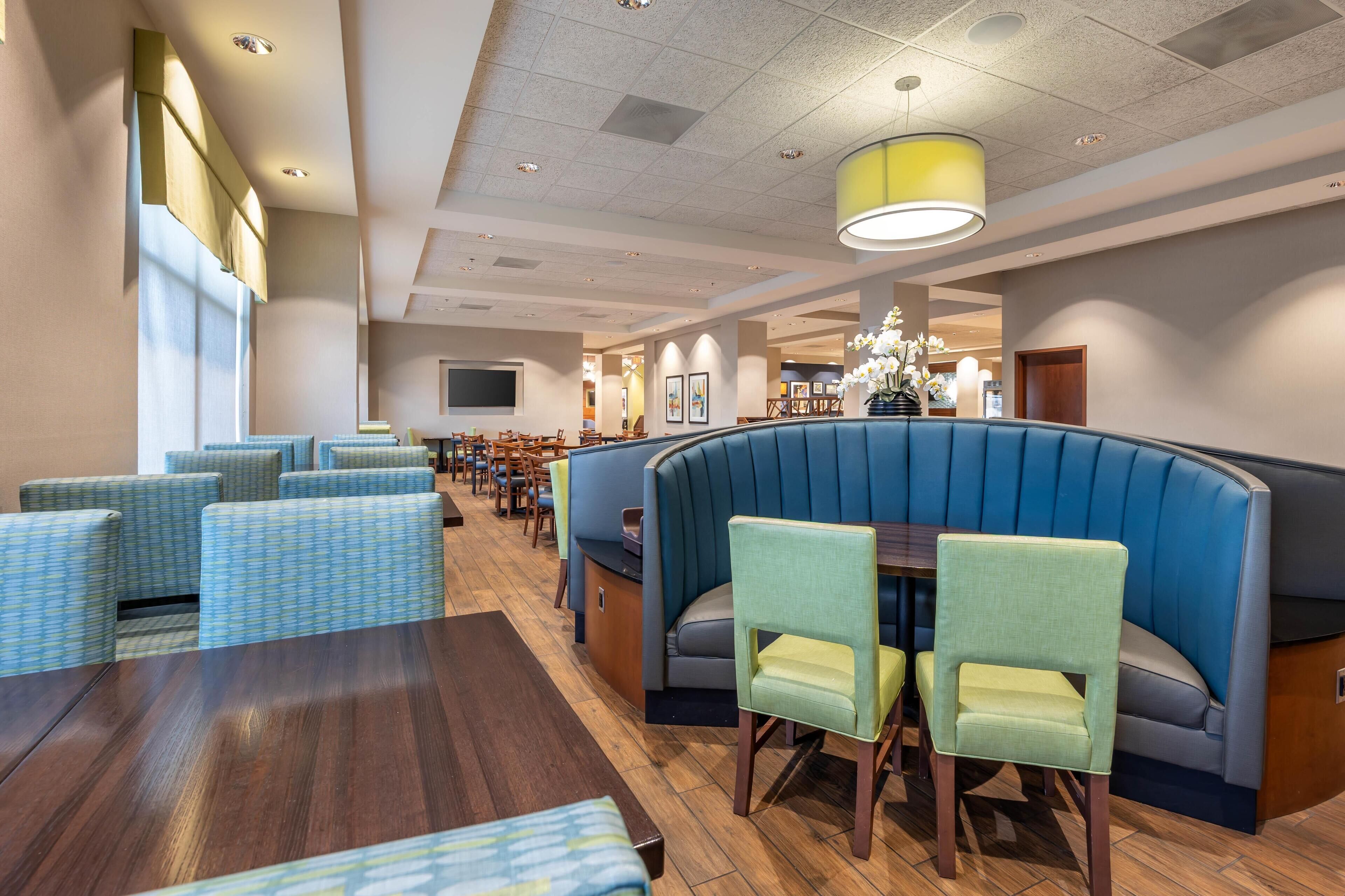 A restaurant with booths and tables, a bar area, and a television screen.