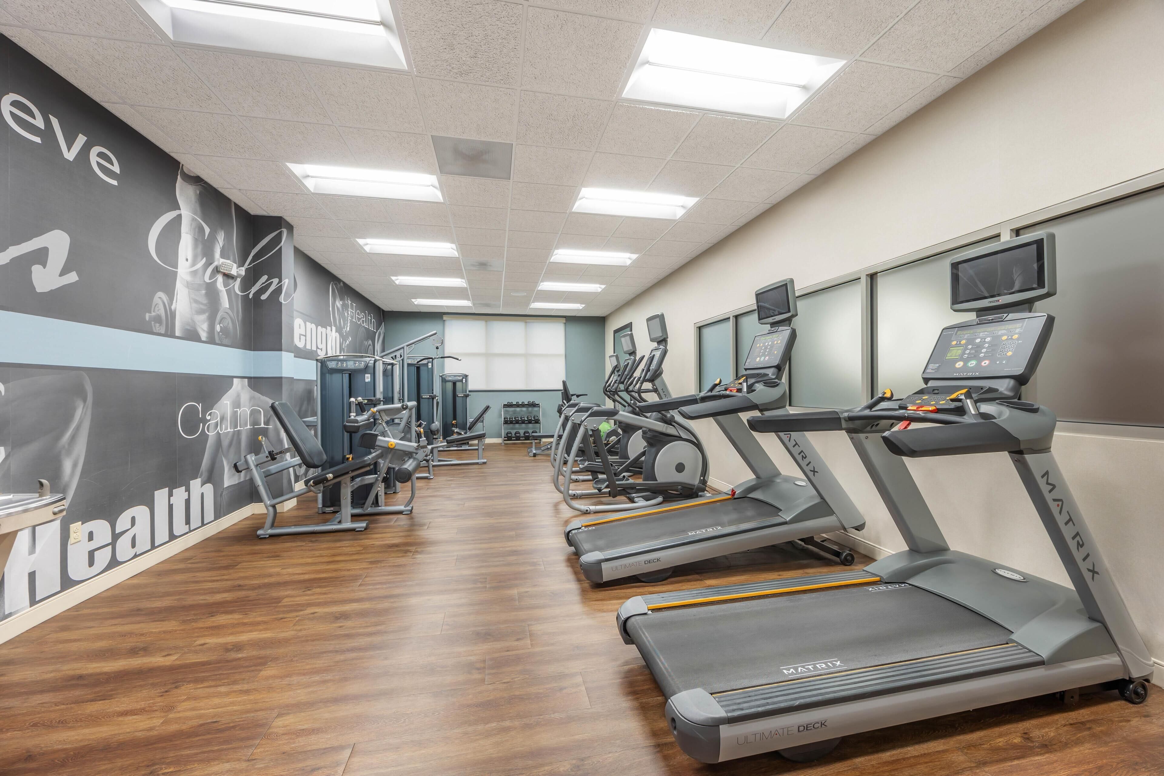 A gym with treadmills, exercise equipment, and a motivational wall.