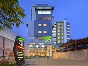 A modern hotel with a prominent sign, large windows, and a paved entrance area. - Whiz Prime Hotel Basuki Rahmat Malang (Malang)