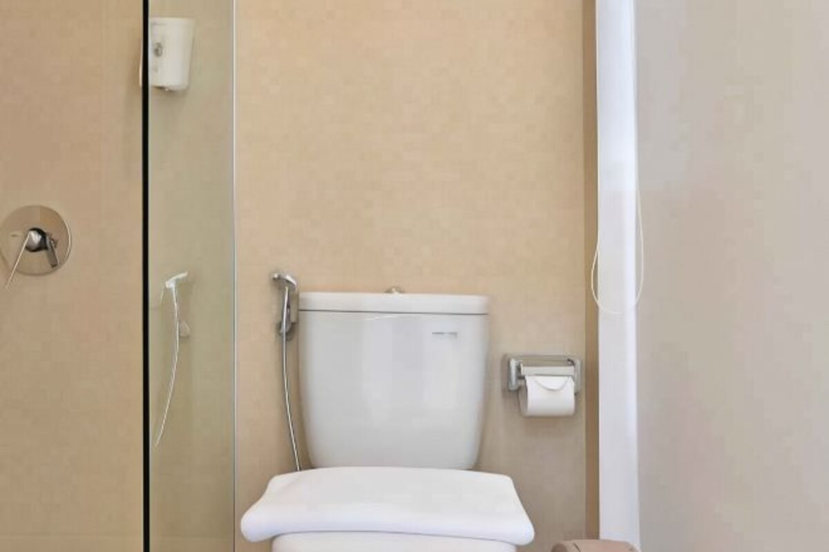 A bathroom with a toilet, a hand dryer, and a paper towel dispenser.