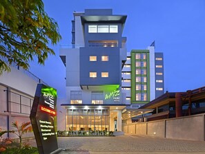 Un hotel moderno con un letrero llamativo, amplias ventanas y un área de entrada pavimentada.