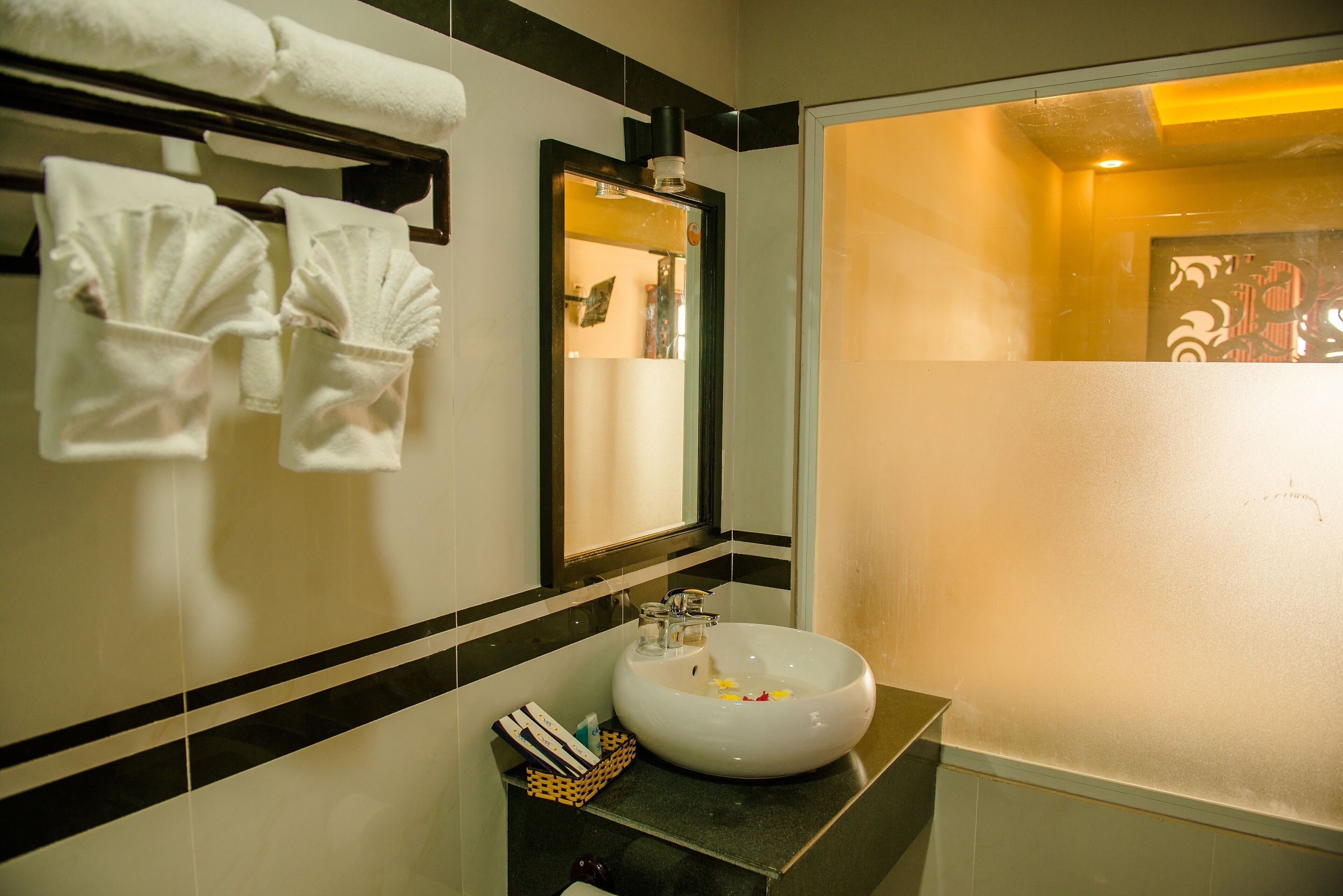 A bathroom with a white sink, a mirror, and towels hanging on a rack.