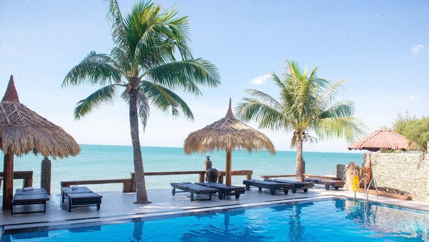 A pool area with lounge chairs and palm trees, overlooking the sea. - Viva Beach Resort Mui Ne (Mui Ne)