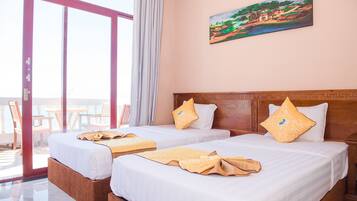 A hotel room with two beds, a painting on the wall, and a balcony with chairs.