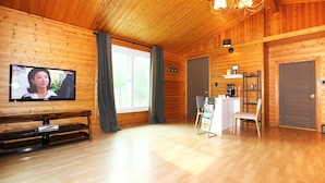 A wooden cabin with a television, a small table, and a reception desk. - Planttrees House (Pyeongchang)