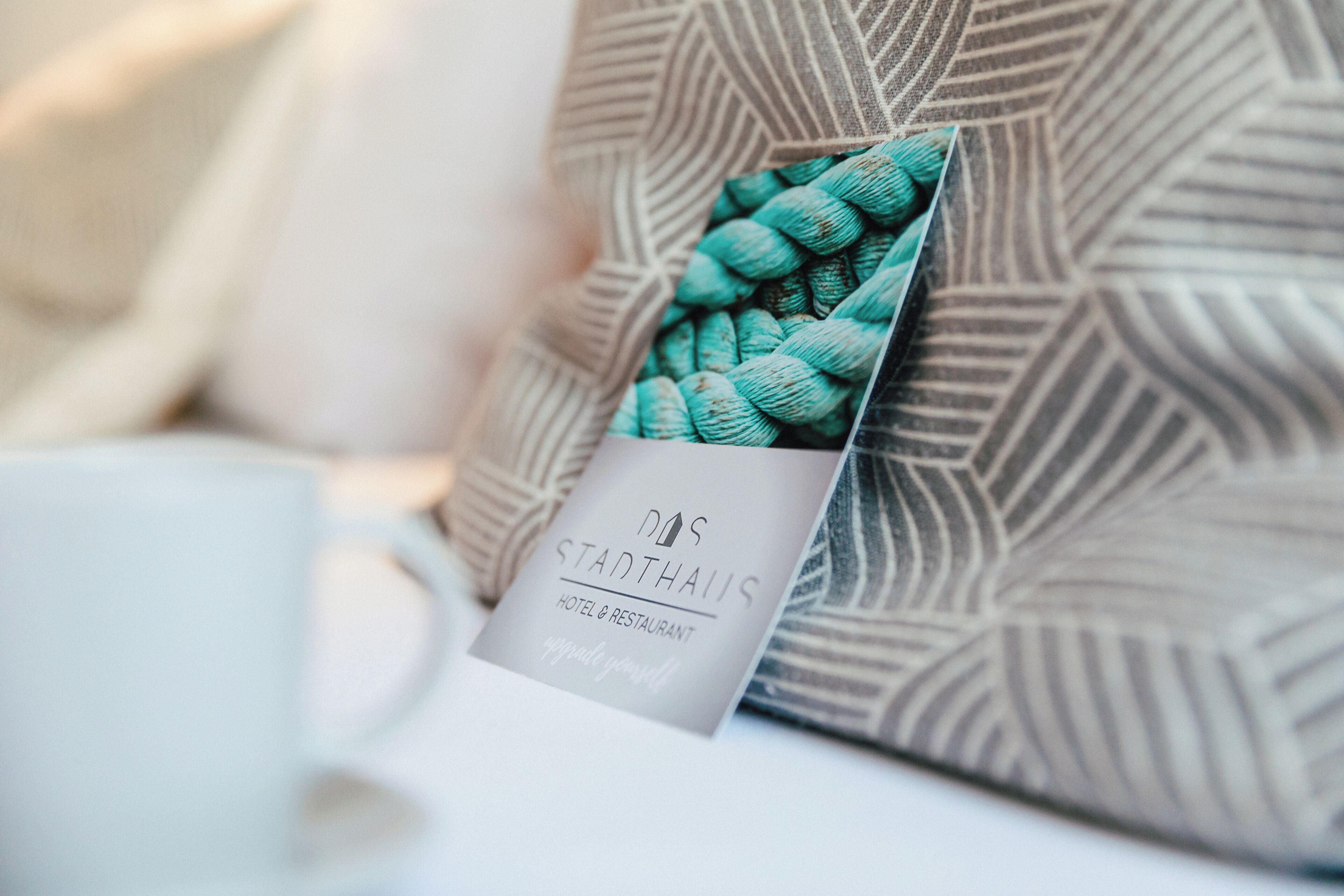 A hotel brochure with a geometric pattern pillow and a white mug.