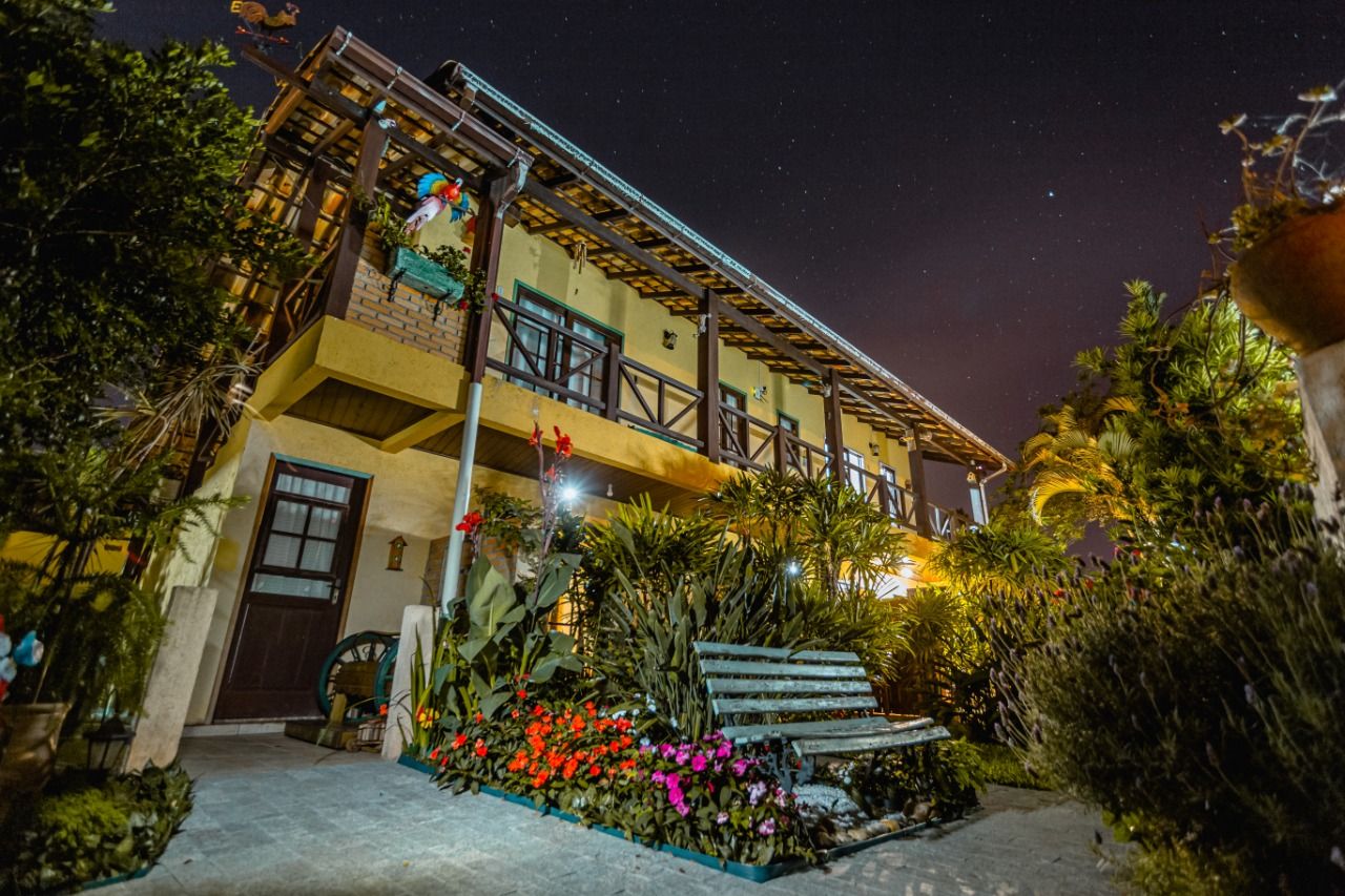 A two-story building with a balcony, surrounded by lush greenery and a variety of plants.