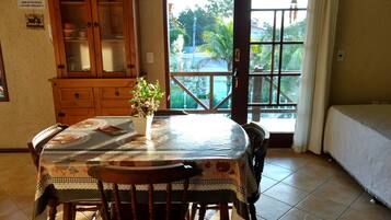 A dining area with a wooden cabinet, a table with a patterned tablecloth, and chairs.