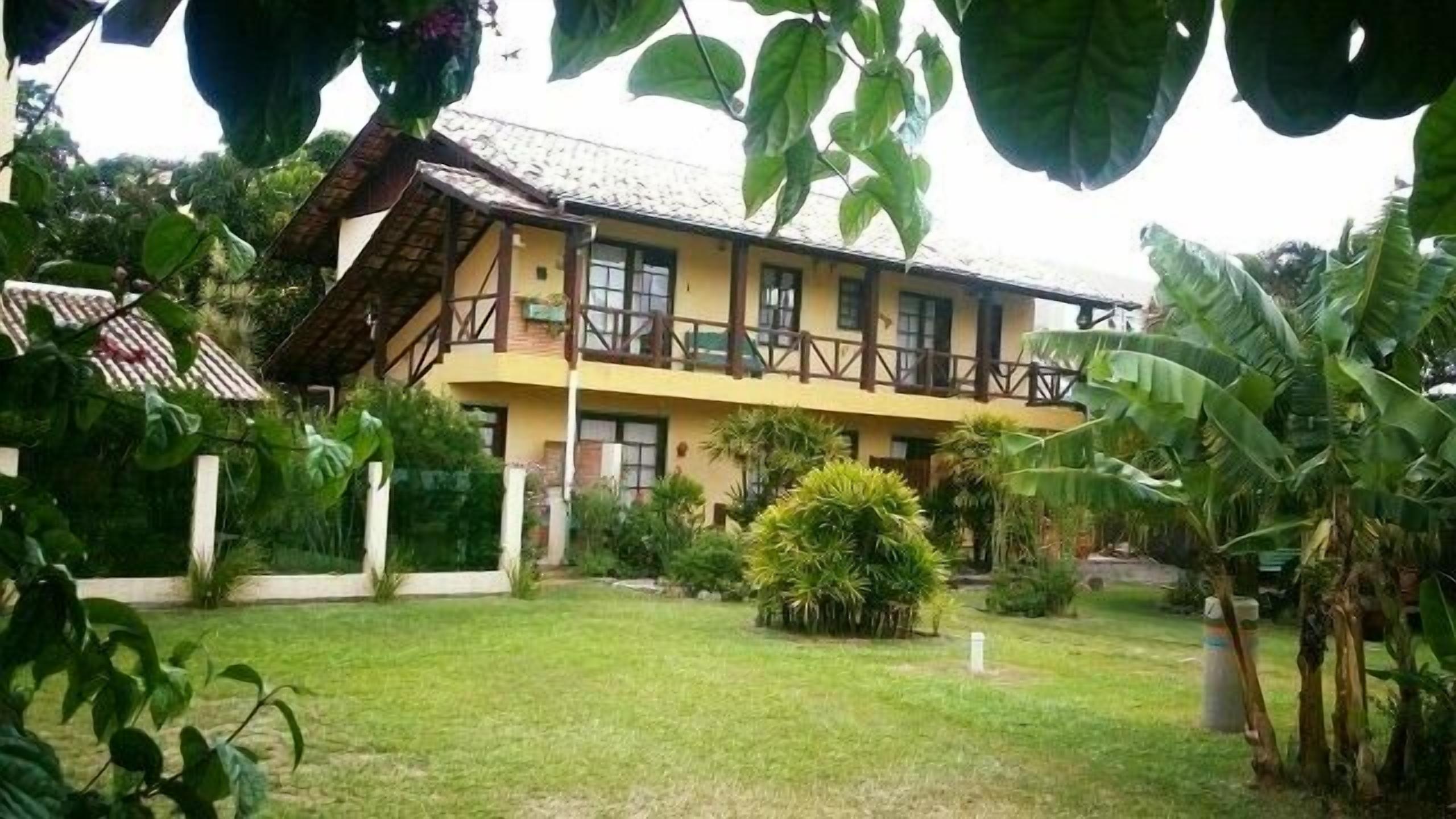 A two-story building with a balcony, surrounded by lush greenery and a well-maintained lawn.