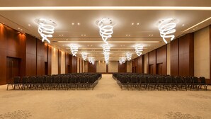 A conference room with rows of chairs, a patterned carpet, and modern spiral ceiling lights. - Kiranshree Grand (Guwahati)