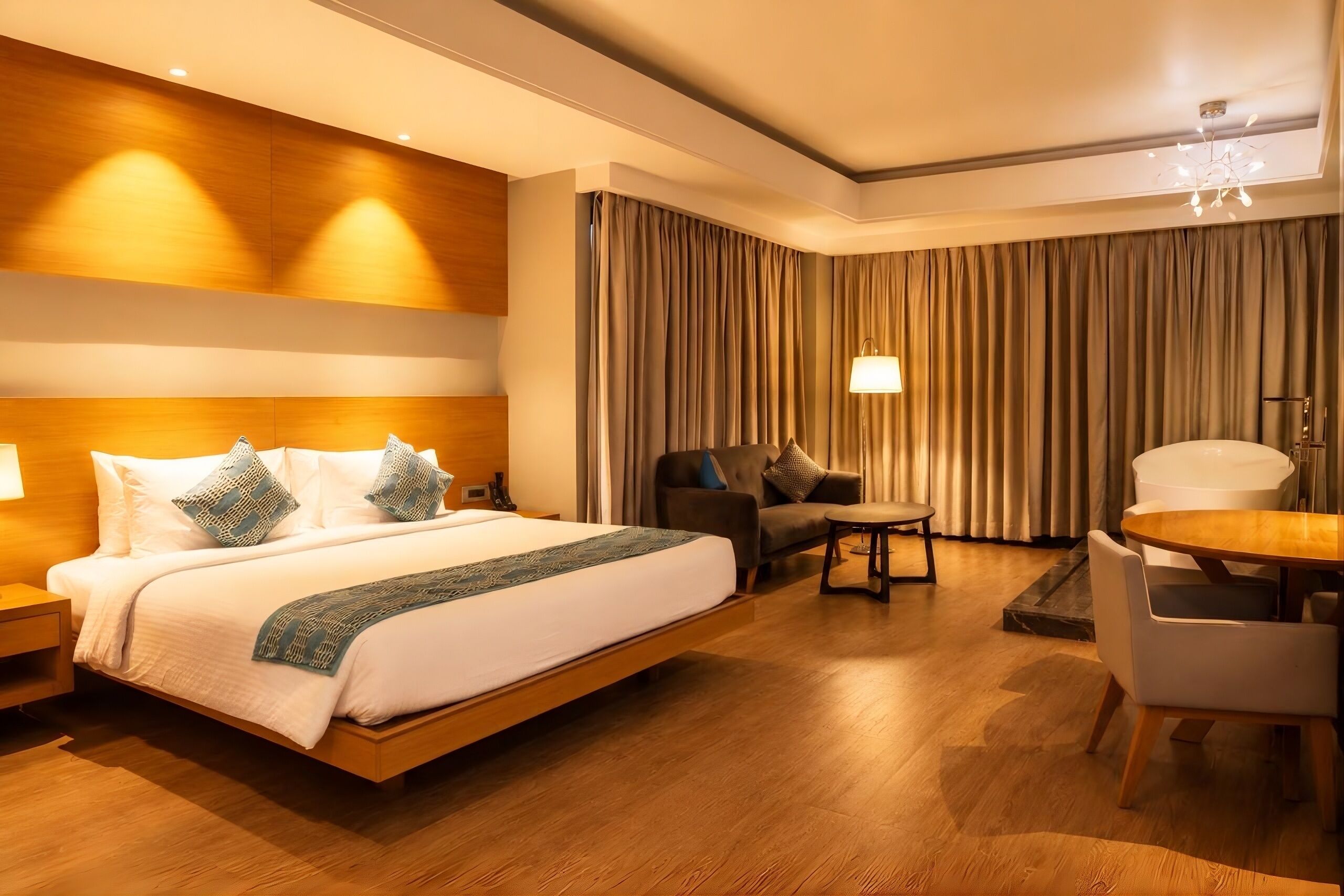 Quarto de hotel com uma cama grande, um sofá, uma mesa de jantar e uma cadeira.