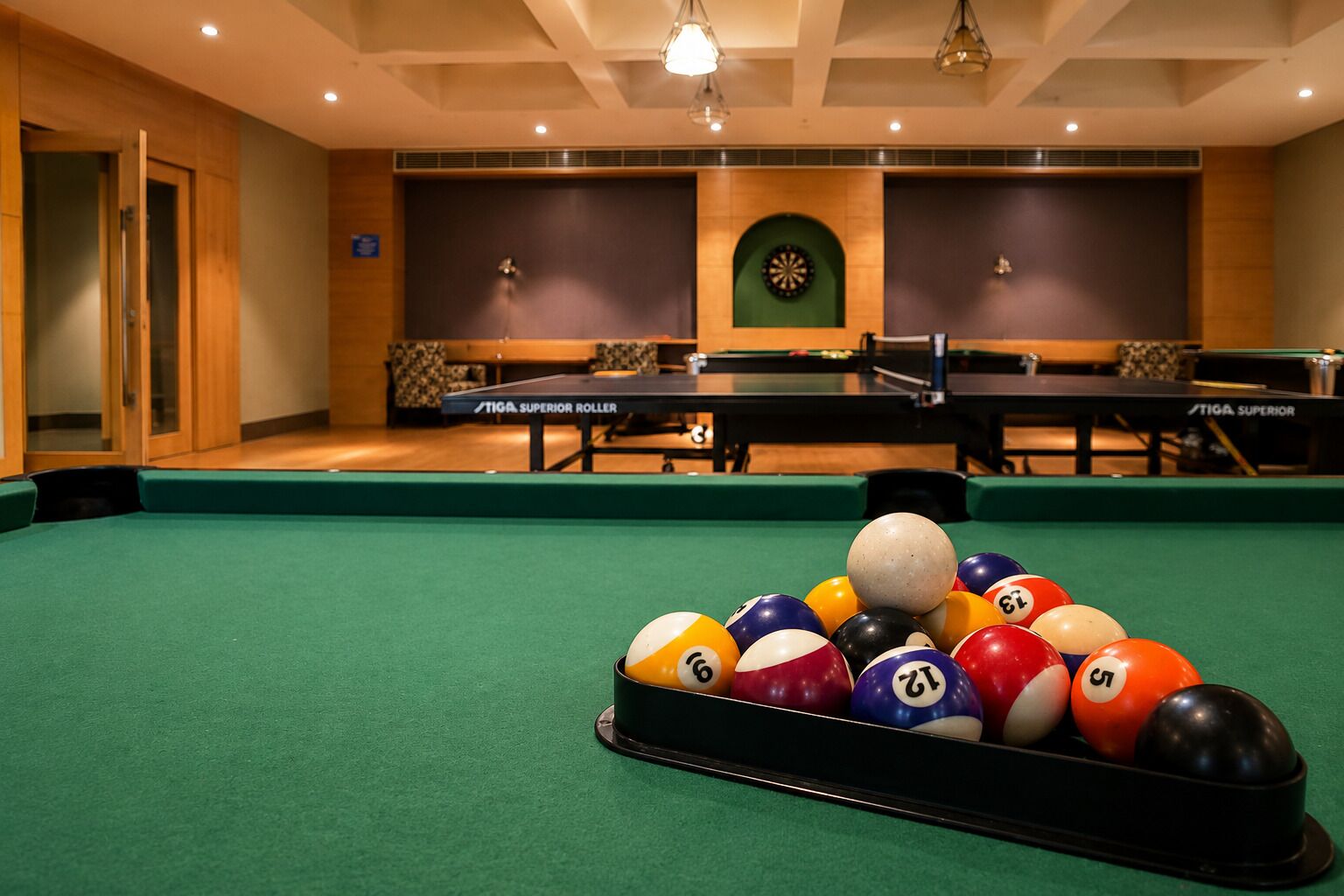 Mesa de billar con un montón de bolas de billar en una habitación con dos mesas y un dardo.
