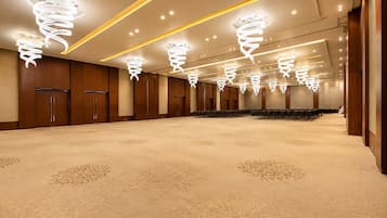 A large conference room with rows of chairs, wooden paneling, and modern spiral ceiling lights.