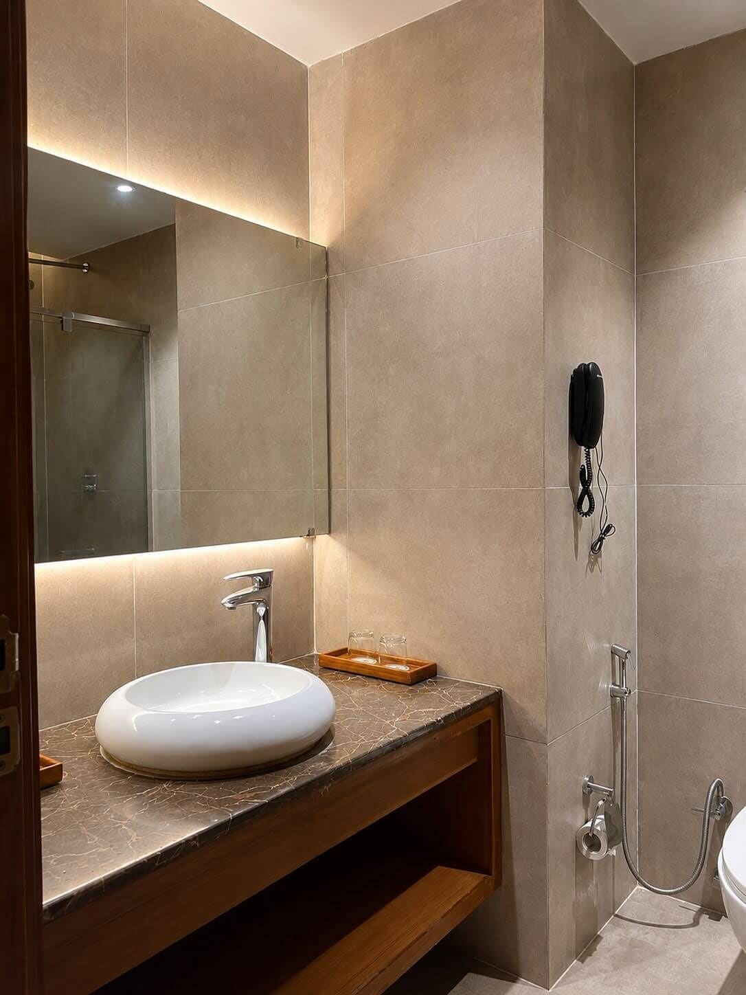 A modern bathroom with a large mirror, a sink, and a shower area.