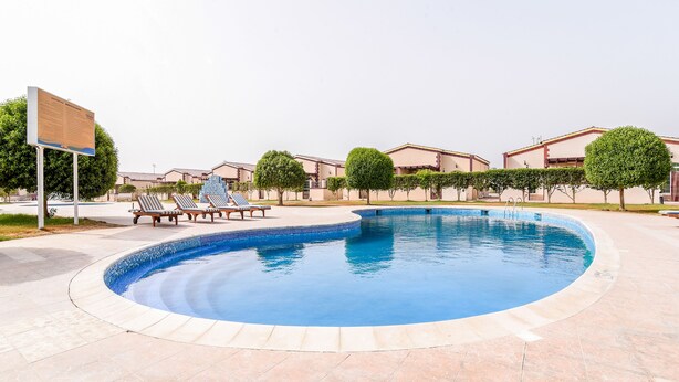 A swimming pool with lounge chairs and a sign. - OYO 231 Holiday Arabian Resort (Sayh Mudayrah)