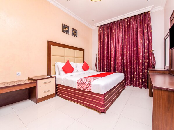 A hotel room with a bed, a nightstand, a desk, and a TV. - OYO 231 Holiday Arabian Resort (Sayh Mudayrah)