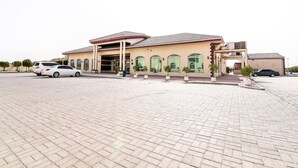 A building with a beige facade, large arched windows, and a covered entrance. - OYO 231 Holiday Arabian Resort (Sayh Mudayrah)