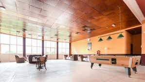 A spacious indoor area with a pool table, comfortable seating, and large windows allowing natural light. - OYO 231 Holiday Arabian Resort (Sayh Mudayrah)