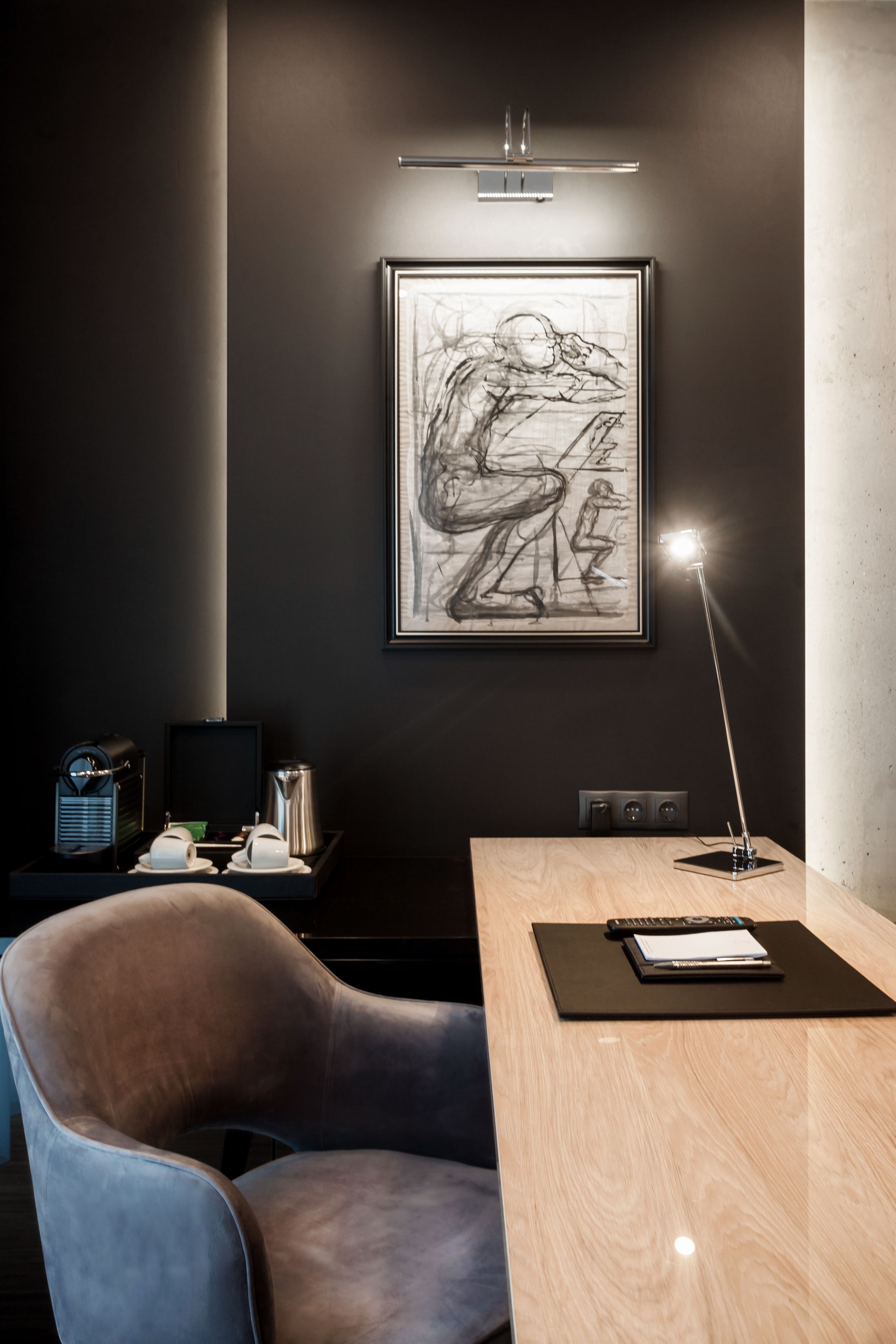Un espacio de oficina moderno con escritorio, silla, obra de arte enmarcada y máquina de café.