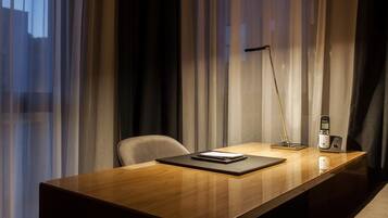 Een moderne hotelkamer met een houten bureau, een stoel, een bureaulamp en een telefoon.