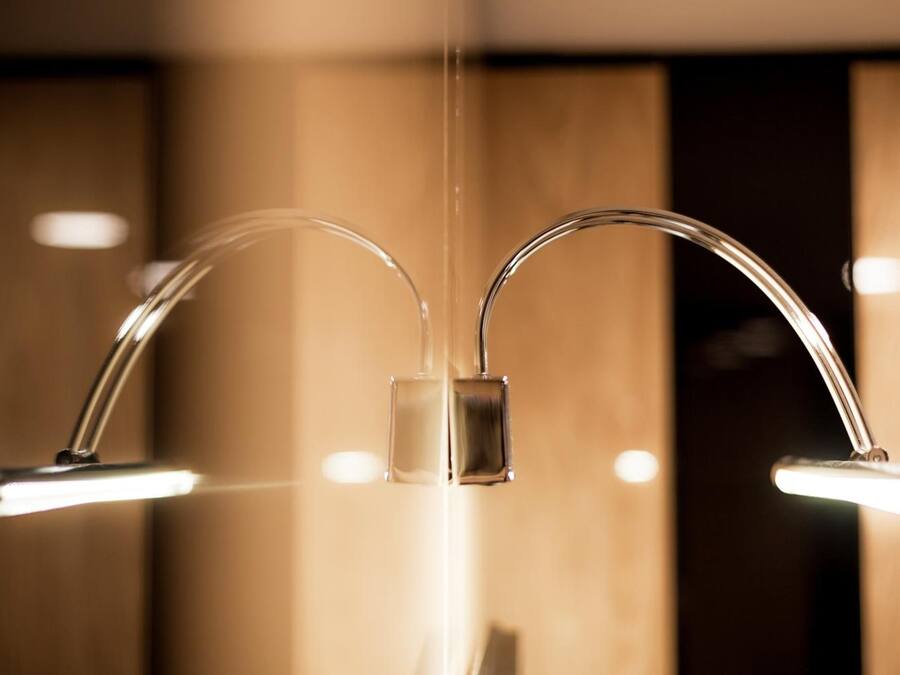 A modern bathroom with two chrome faucets and a central control panel.